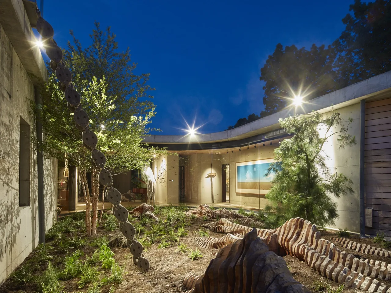 The Hudson Concrete House features a curved indoor garden courtyard with sculptural art and concrete walls.