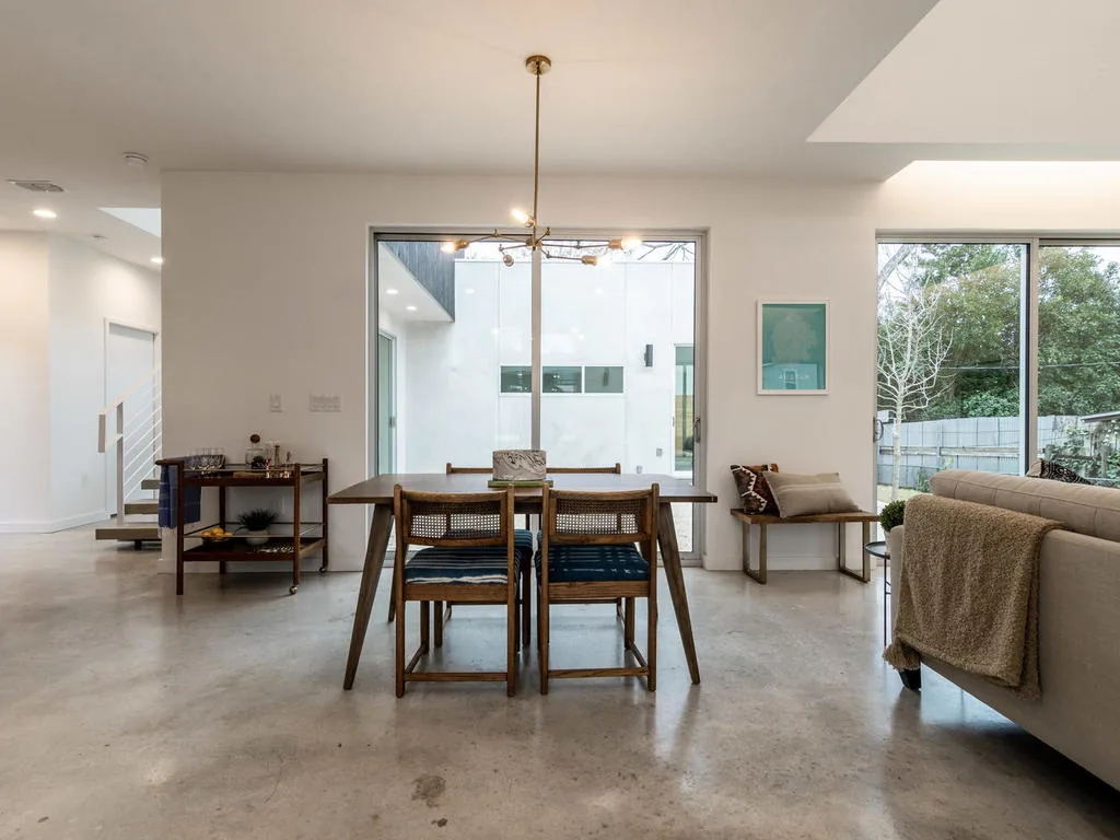 Dining room with wood furniture and large glass doors framing a courtyard in a modern home by KRDB.