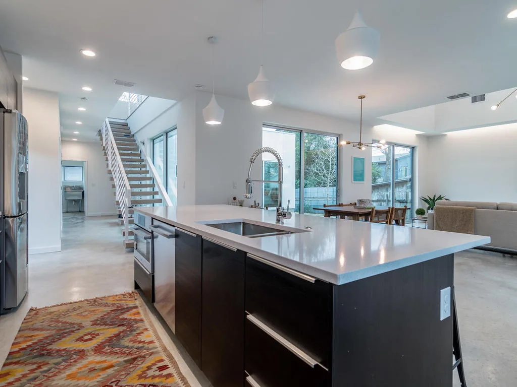 Modern kitchen and dining space with a large island and staircase featuring horizontal clerestory windows.