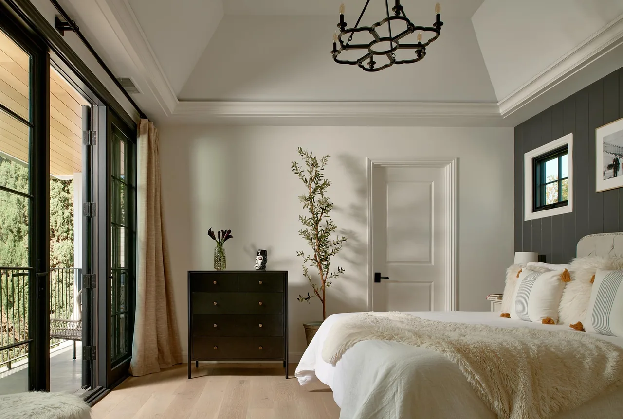 Bedroom in Clybourn Manor features a vaulted ceiling and black framed glass doors leading to a balcony.