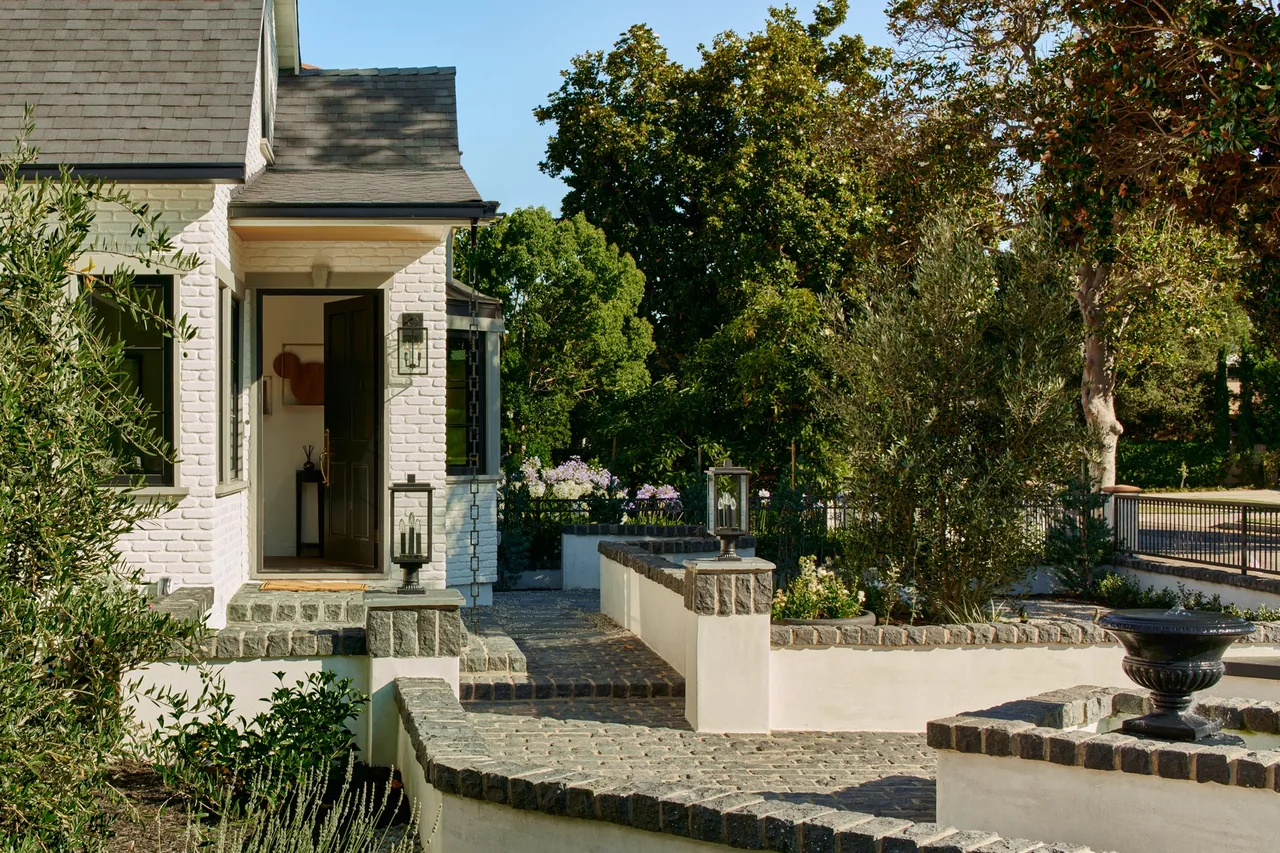 The Clybourn Manor features a steep roof pitch, a stone courtyard, and landscaped planting areas by Kurt Krueger Architect.