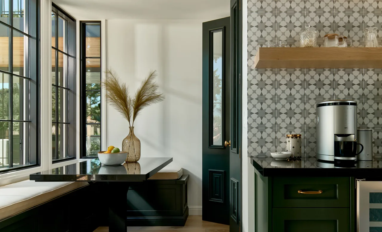 A kitchen nook with black window frames, green cabinetry, and patterned tile backsplash in a modern style.