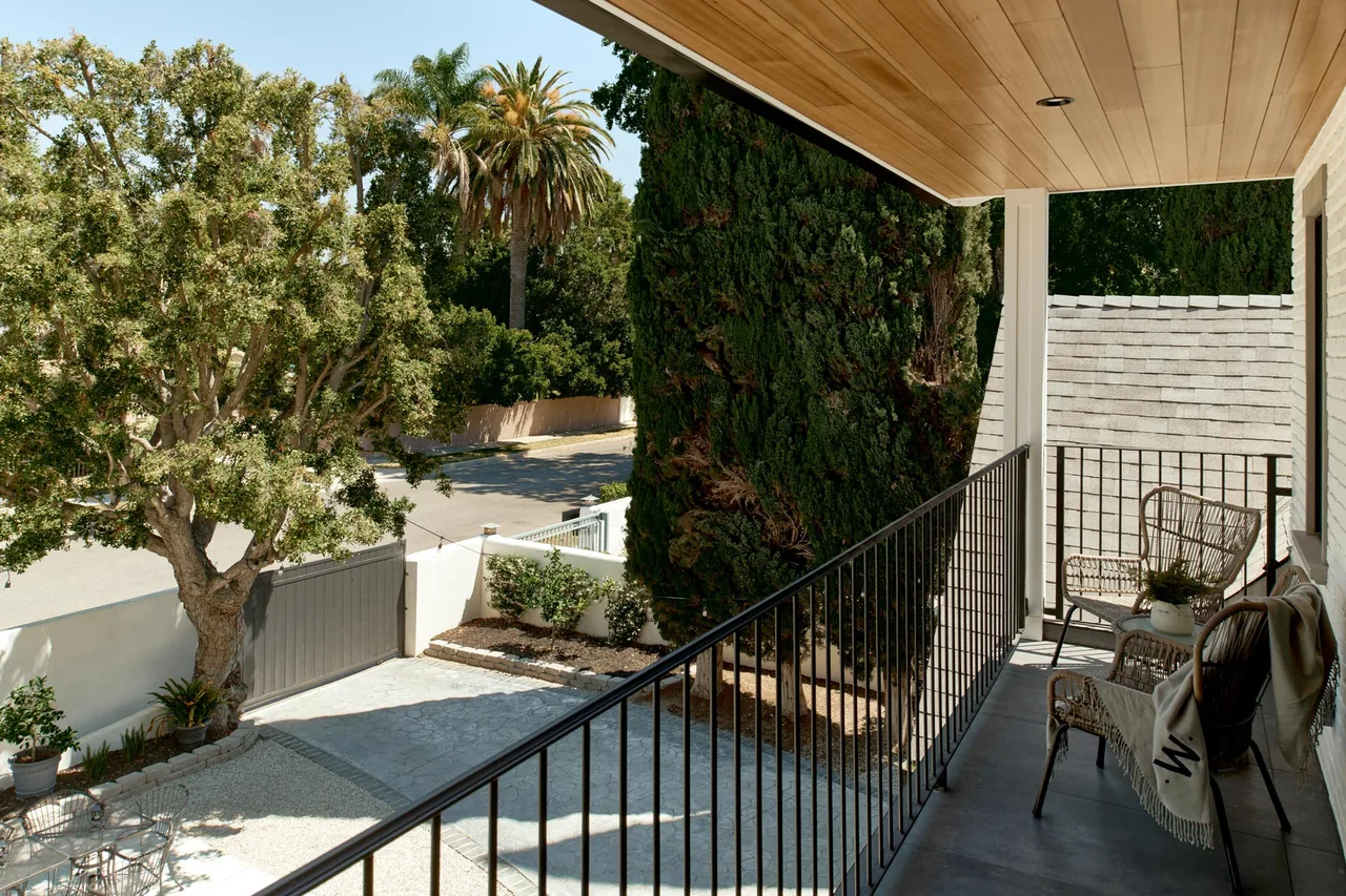 Covered balcony with wicker chairs and black metal railing at CLYBOURN MANOR by Kurt Krueger Architect