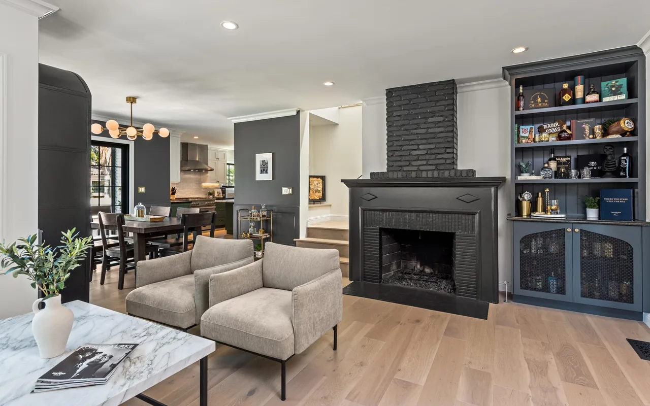 The living area includes a black brick fireplace and built-in shelving adjacent to the dining space with a modern light fixture.