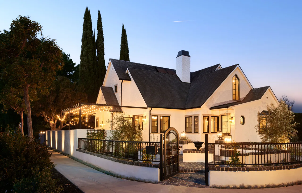 The Clybourn Manor features white brick exterior, steep gable roofs, and an illuminated gated courtyard in Los Angeles.