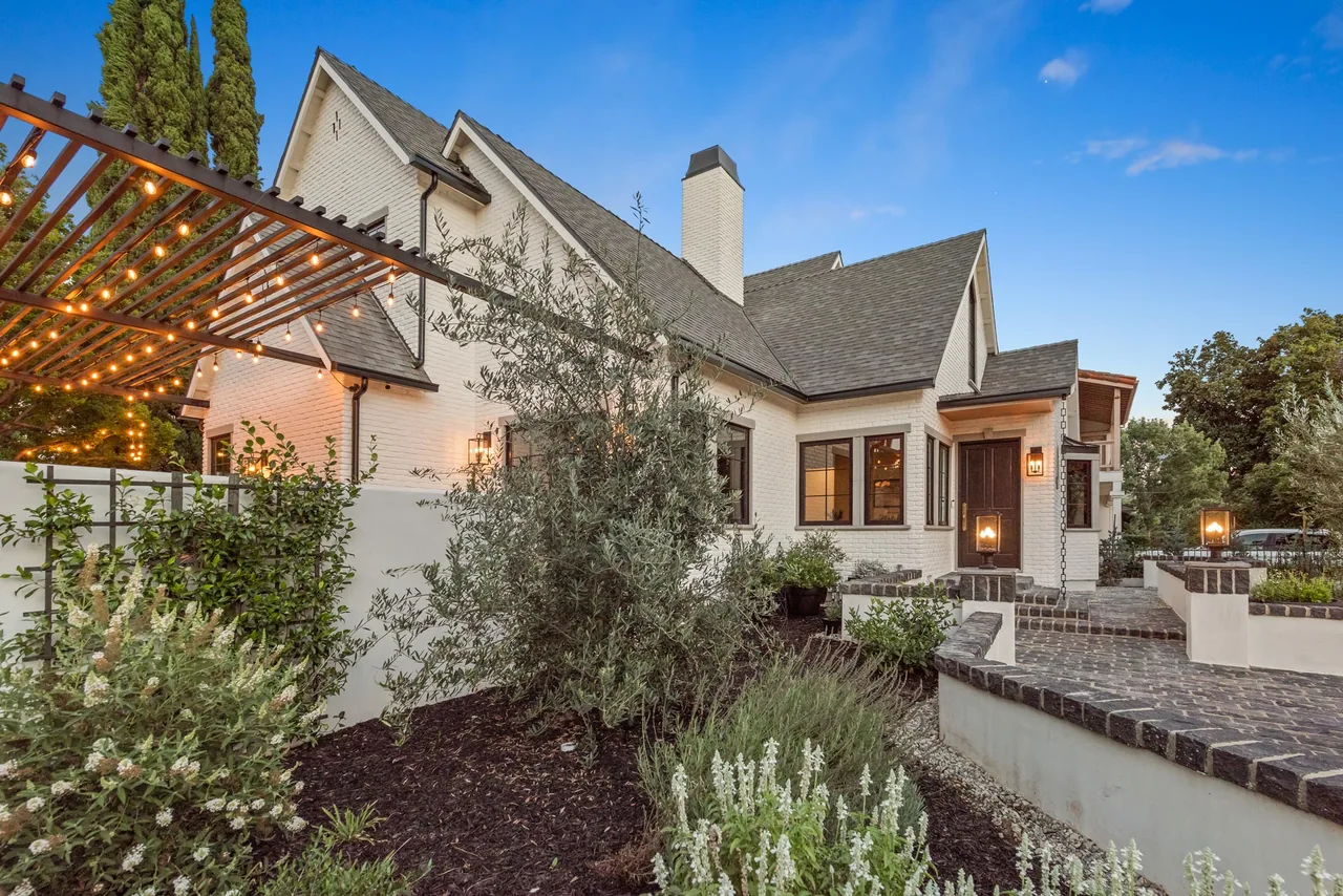 White brick manor with steep roof gables and illuminated brick coping around the courtyard.