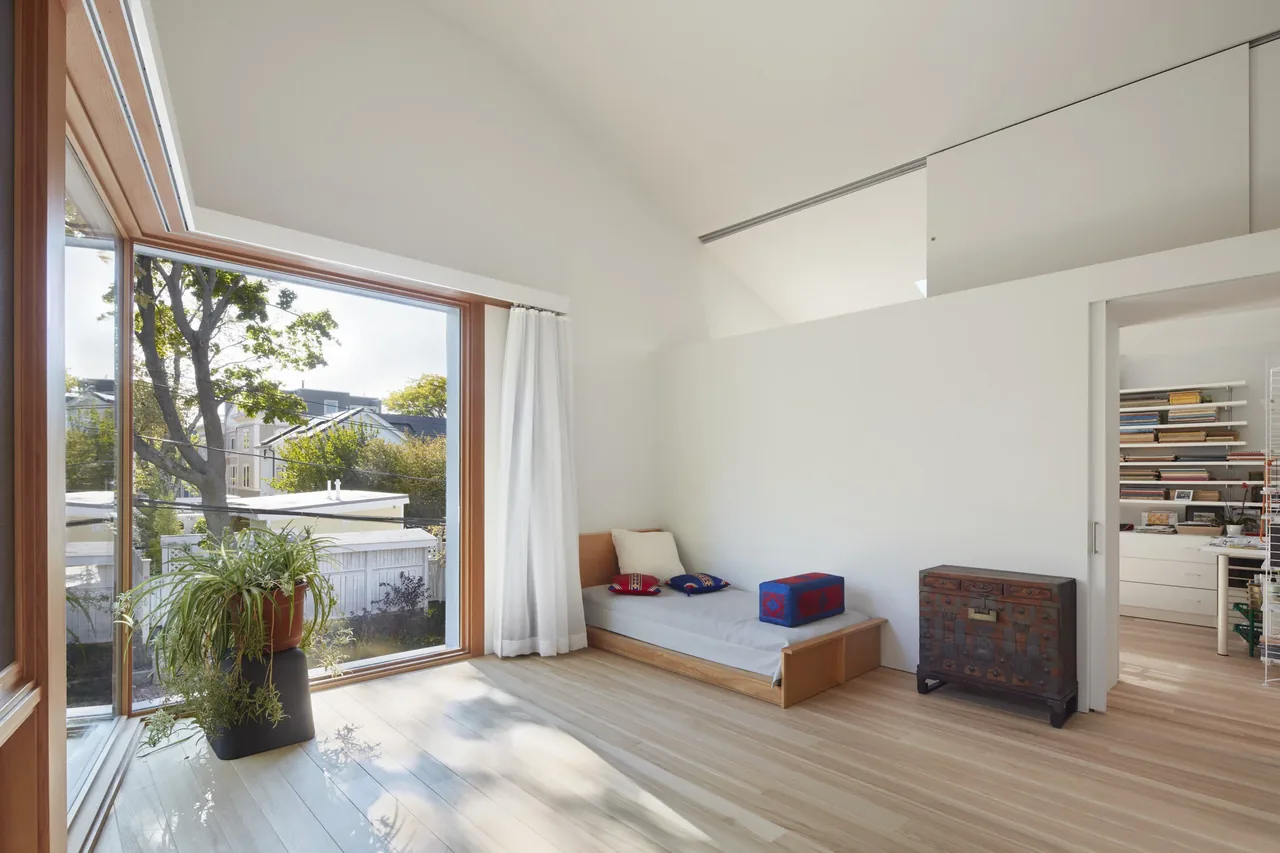 Living space in House II by Kyu Sung Woo Architects features a large corner window with wood framing and minimalist furniture.