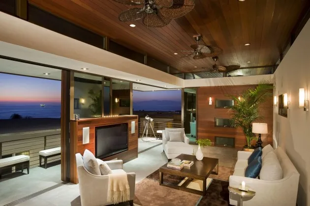 Living room with wooden ceiling, ceiling fans, and a view of the ocean through sliding glass doors.