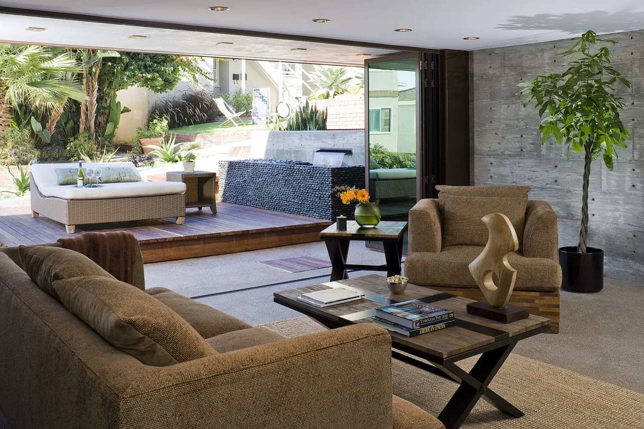 Living room opens to a raised outdoor deck with a lounge chair, featuring seamless indoor-outdoor connection.