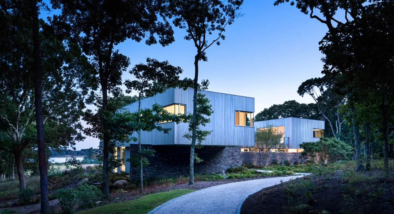 Hill House features wood siding and a stone base with large windows, designed by Leroy Street Studio.