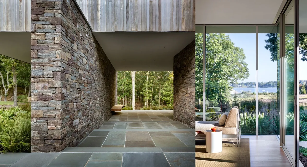 Stone retaining wall passage contrasts with a floor-to-ceiling glass window providing lake views at Hill House.