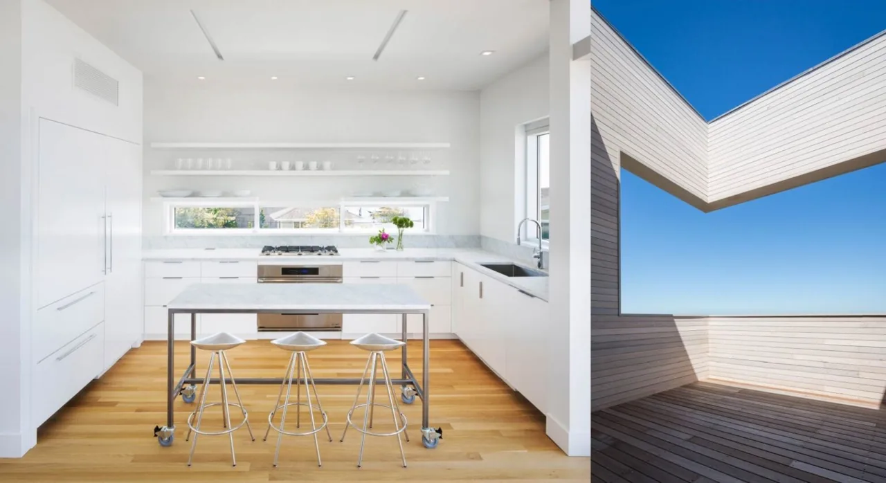 The Cube House kitchen features clean white cabinets and a marble island, adjacent to a spacious wooden deck with cable railing and wide sky views.