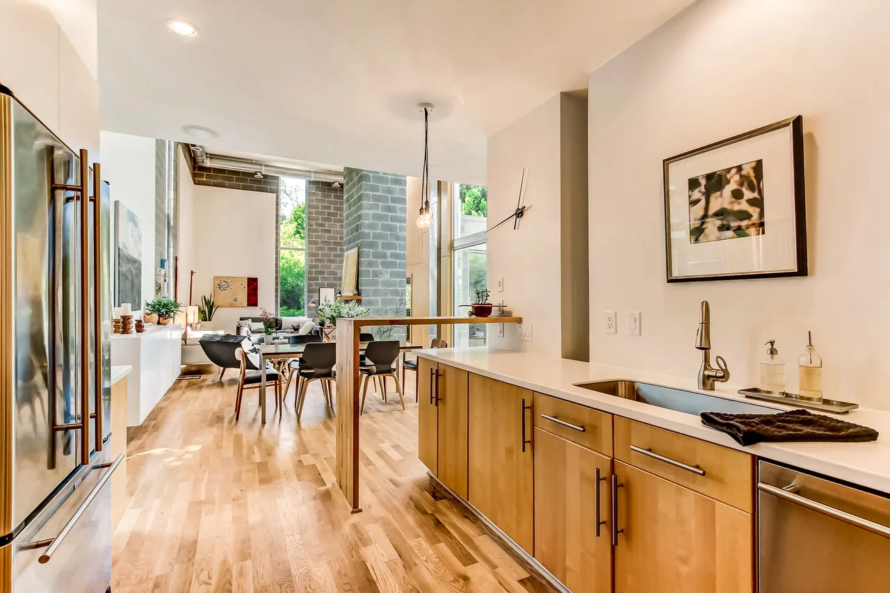 Modern kitchen and living area with wood flooring and exposed gray concrete block tower at 490 Glen Iris by Lightroom.