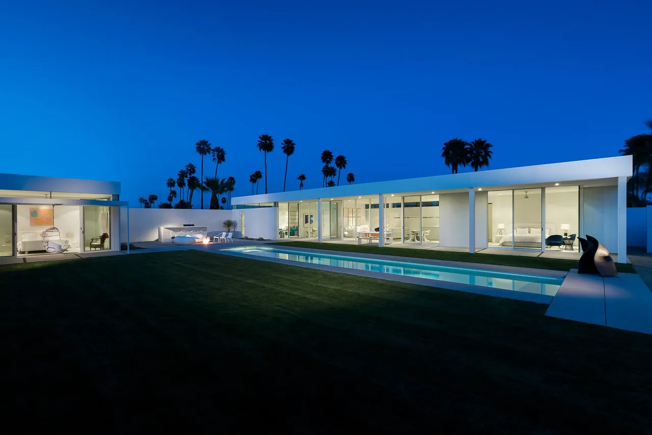 The Palm Springs Residence features a modern flat roof design with extensive floor-to-ceiling glazing and a pool in the outdoor living space.
