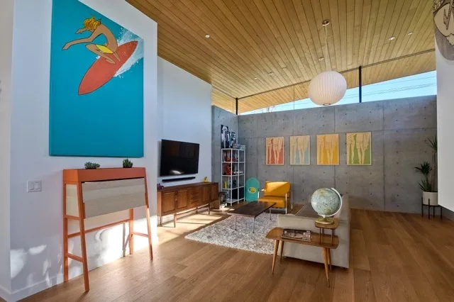 Living room in Aa House with wood ceiling overhang, concrete wall, and midcentury modern furniture by Lloyd Russell AIA.