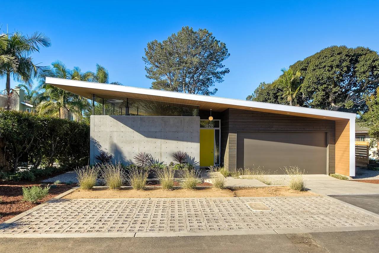 The Aa House features a slanted flat roof, concrete wall, and a dark garage door with wood siding accents.