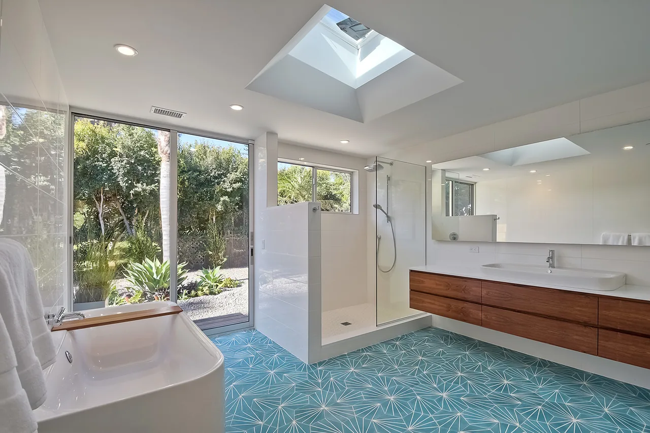 Bathroom features a walk-in shower, freestanding tub, skylight, and large window with garden view.
