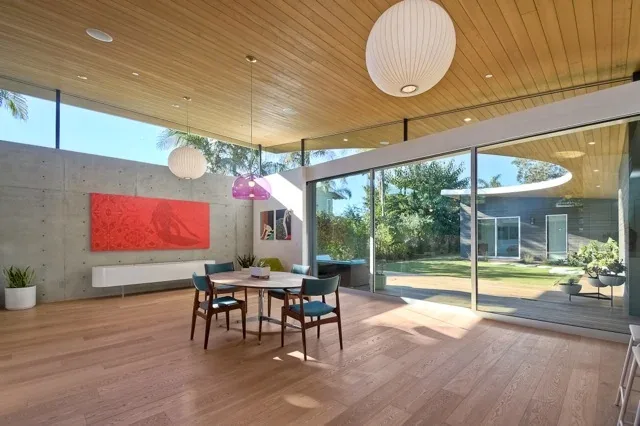 Dining space features wood ceiling and large floor-to-ceiling glass doors that open to an outdoor patio area.