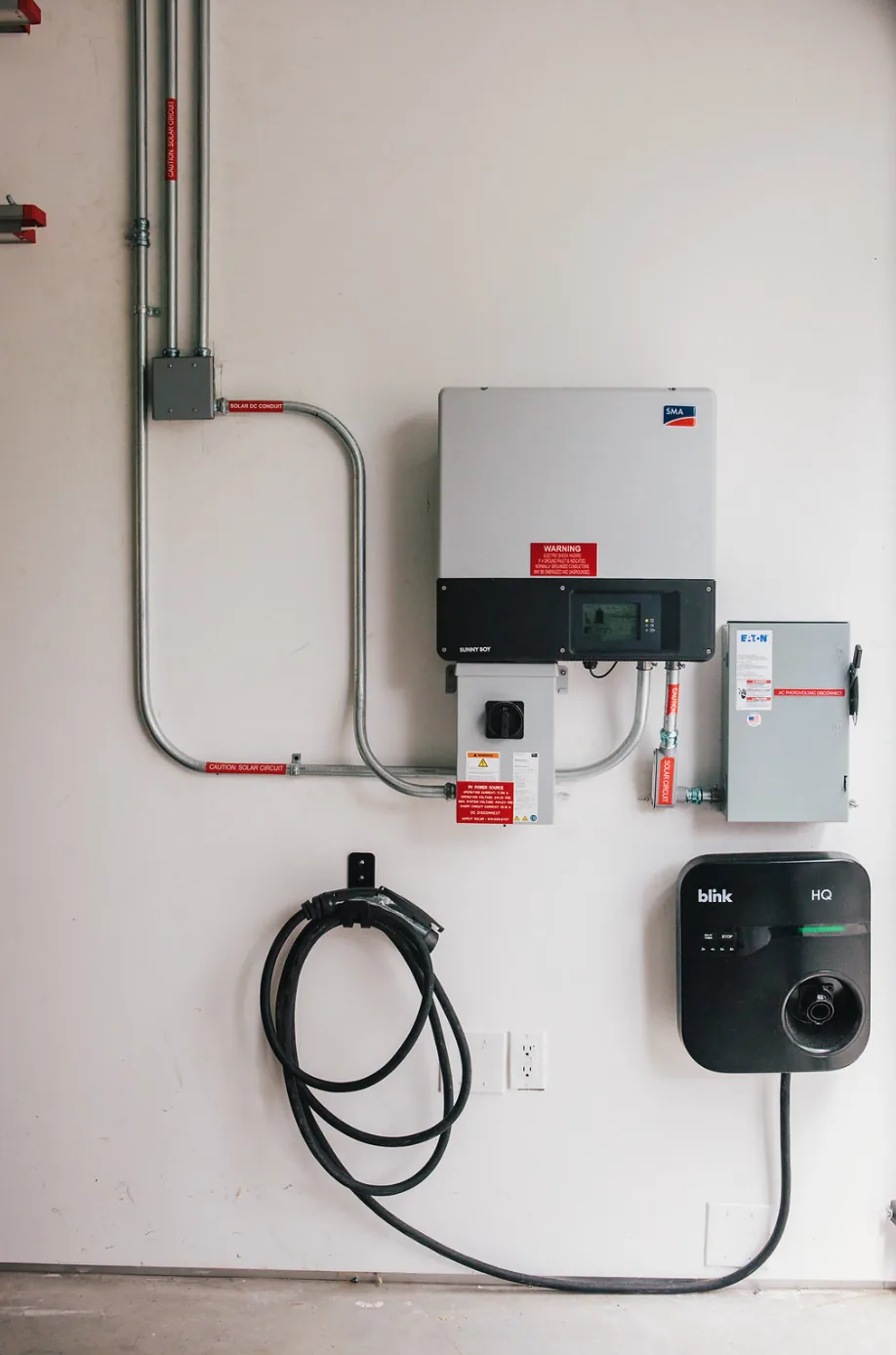 Electrical control and charging equipment with solar circuit conduits on a plain wall.