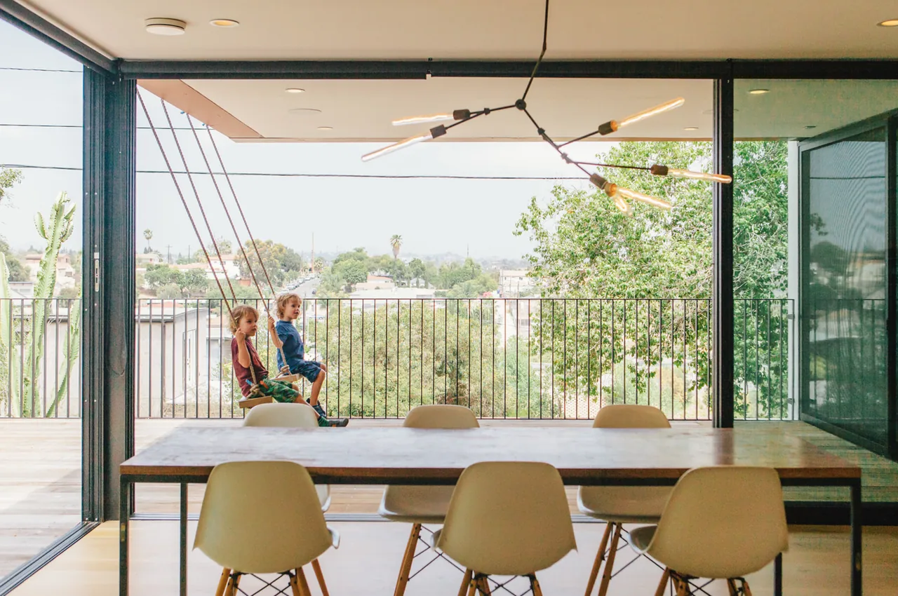 Dining area opens to a covered balcony with hanging swings and city views.