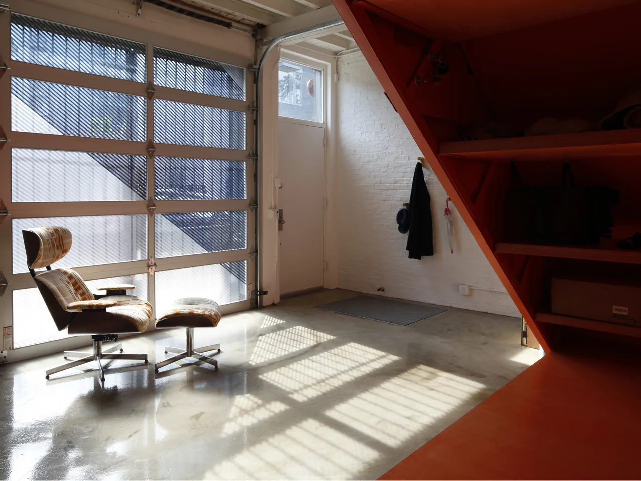 IRVING PLACE CARRIAGE HOUSE entry area with metal staircase and glass garage door creating patterned light and shadow.