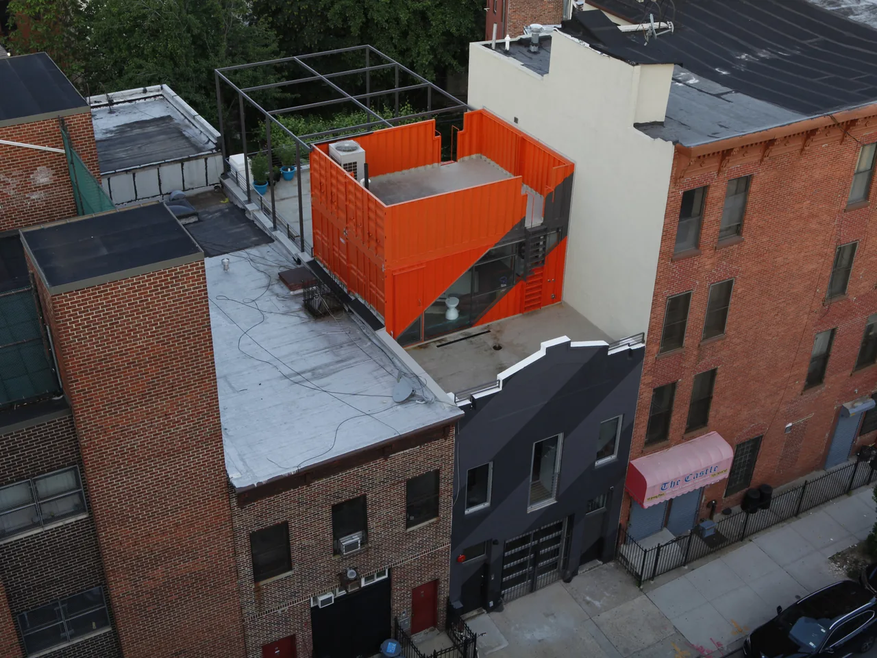 The Irving Place Carriage House features a distinctive black facade with an orange rooftop addition in an urban setting.