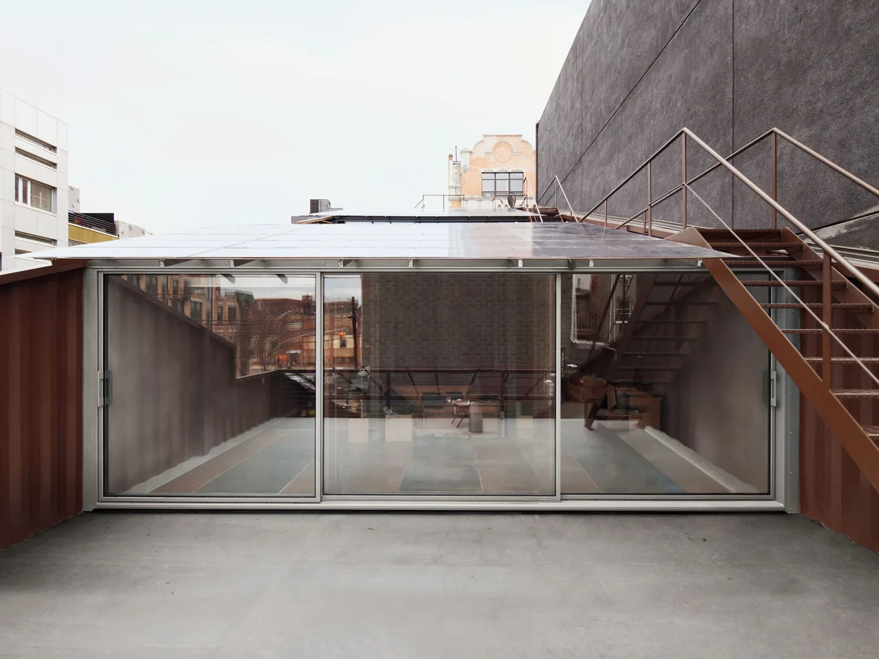 The Carroll House rooftop features glass sliding doors and an exterior metal staircase, highlighting its modern industrial style.