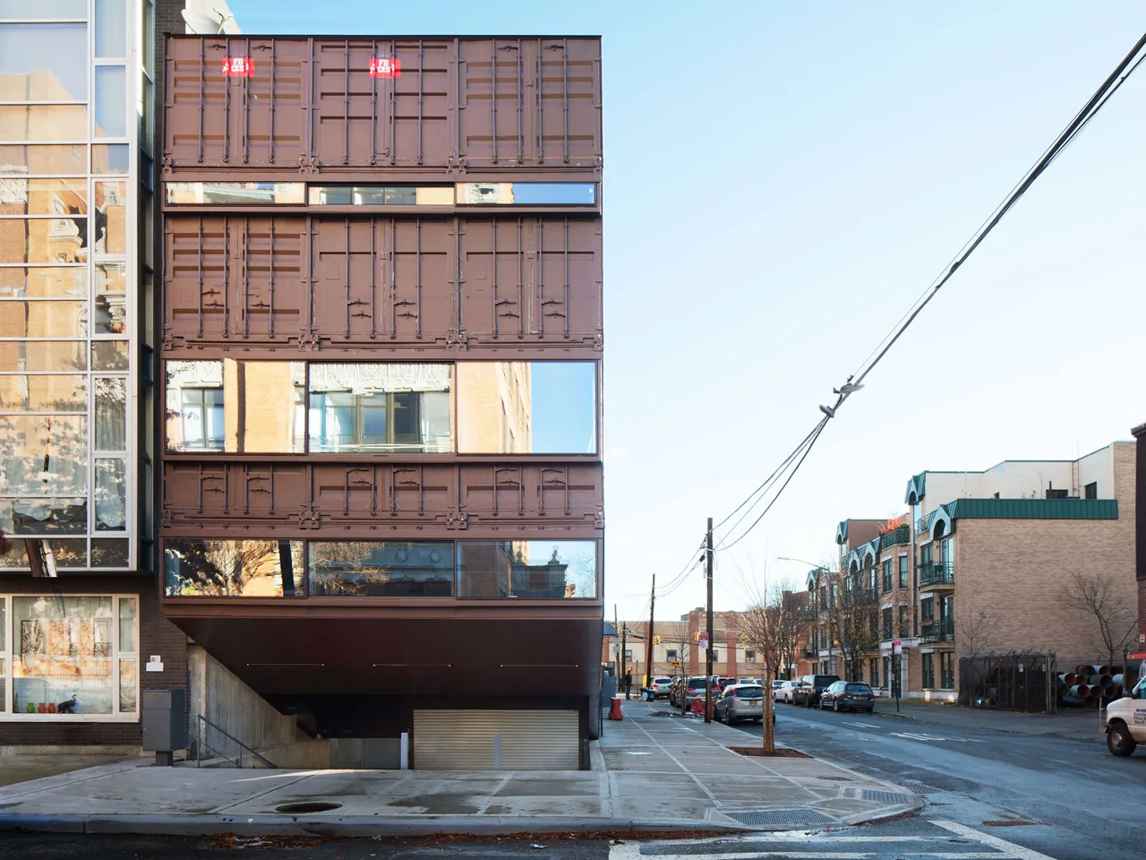 CARROLL HOUSE features a facade resembling shipping containers with narrow horizontal windows reflecting the street.