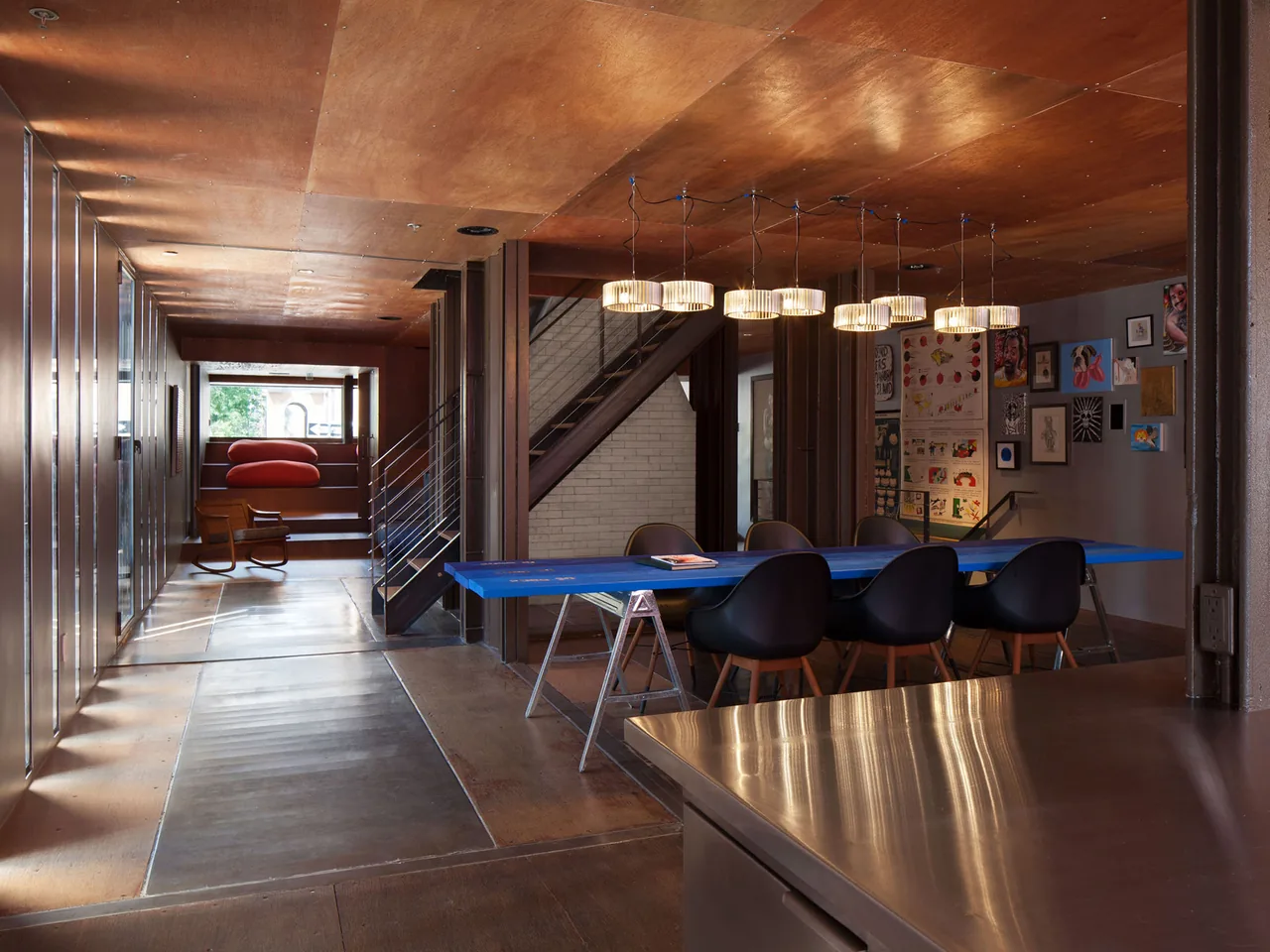 Dining area with a blue table and black chairs illuminated by pendant lights at Carroll House.