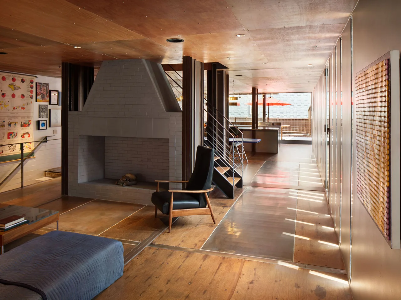 Living room features a large gray brick fireplace and a metal staircase leading to an outdoor area with a bright orange umbrella.