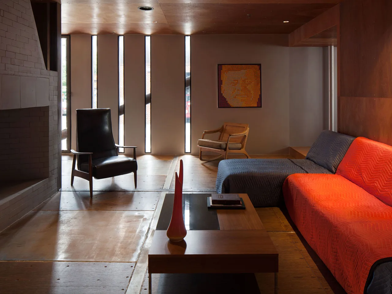 Living room in CARROLL HOUSE features vertical slit windows and a mix of modern seating with wood accents.