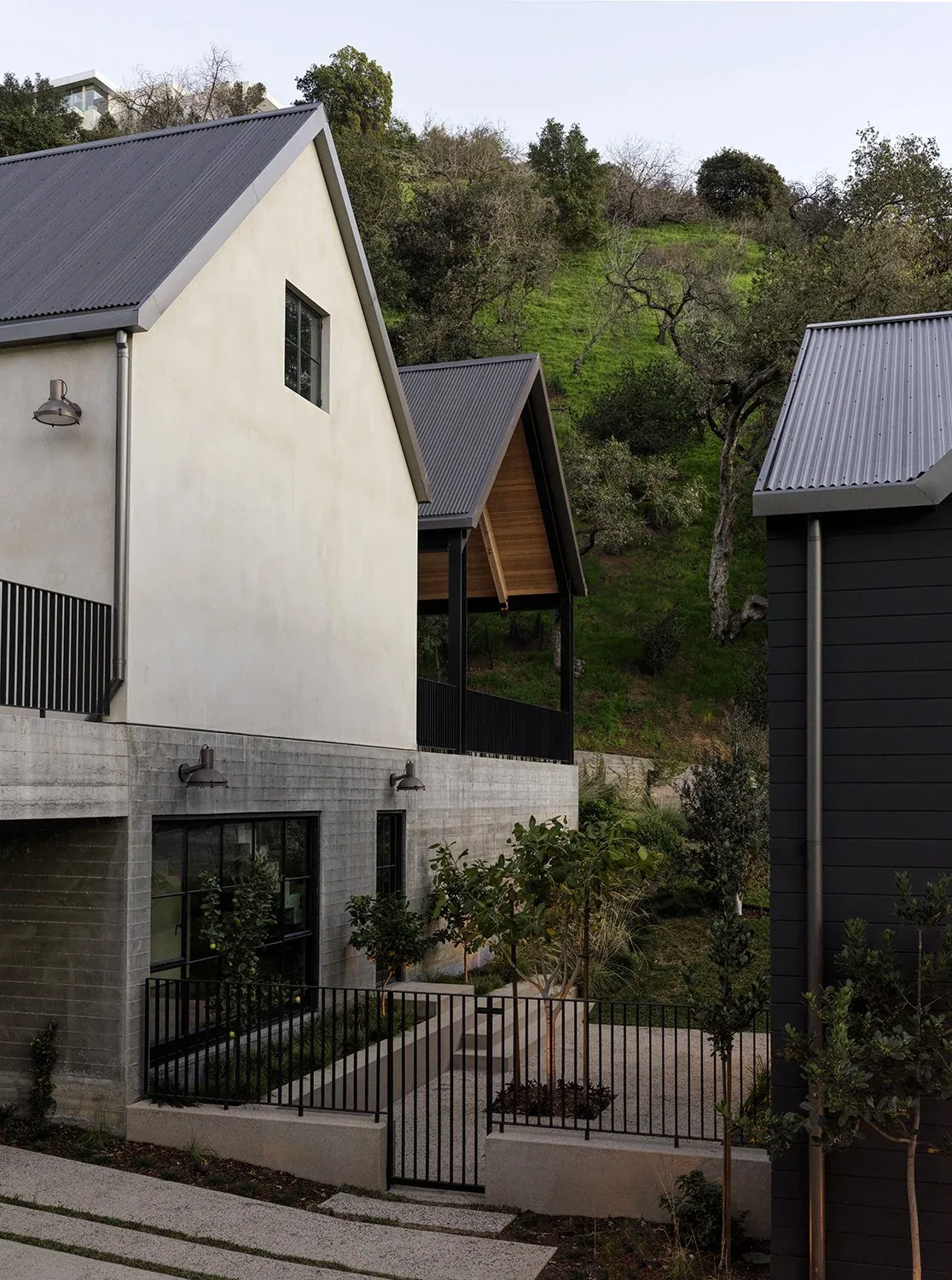 The Canyon House exterior features a mix of concrete and stucco walls with metal roofs and black framed windows.