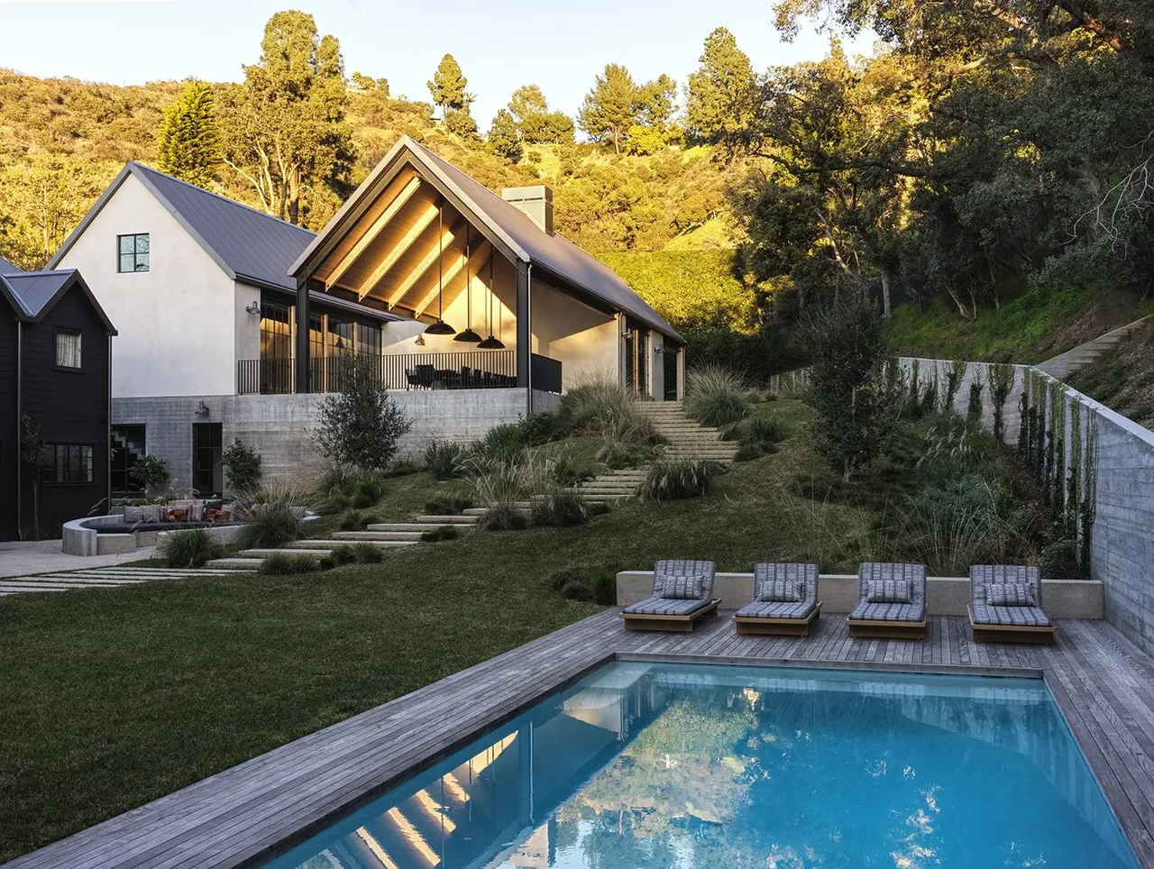 Canyon House features steep gable roofs and a pool beside terraced landscaping in a hillside setting.