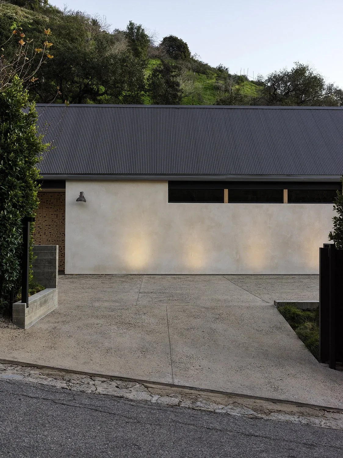The Canyon House features a sloped metal roof and textured light wall with a concrete driveway.