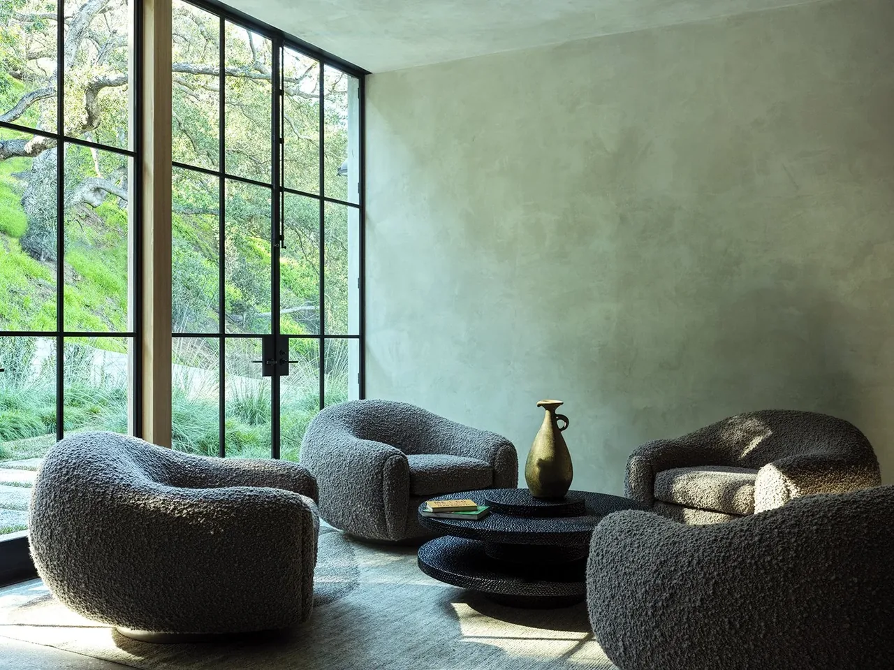Sitting area in Canyon House featuring textured armchairs and a black coffee table next to floor-to-ceiling windows.
