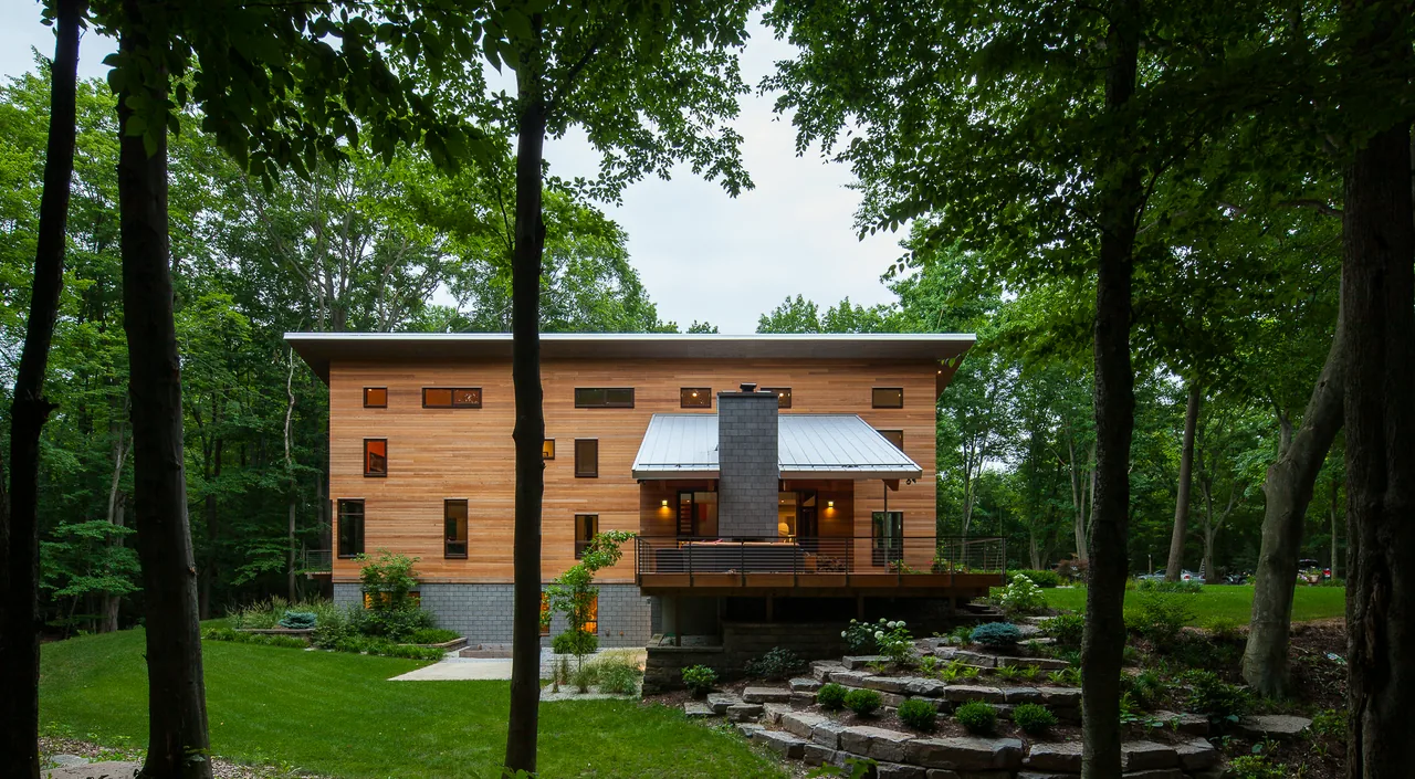 The Pigeon Creek Residence features wood siding, a metal roof, a concrete block fireplace, and a landscaped yard with stone retaining walls.