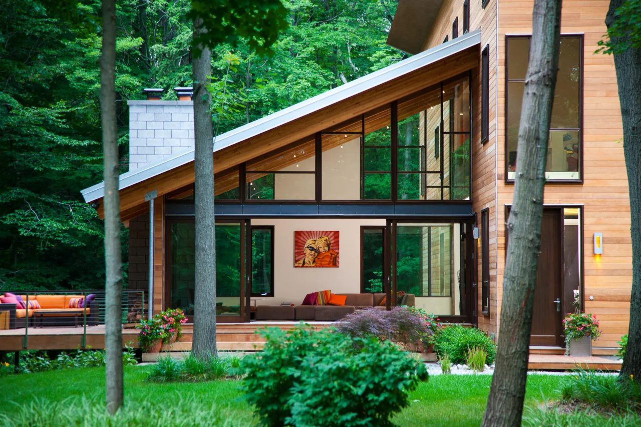 Pigeon Creek Residence features an angled shed roof with floor-to-ceiling black window frames and horizontal wood siding.
