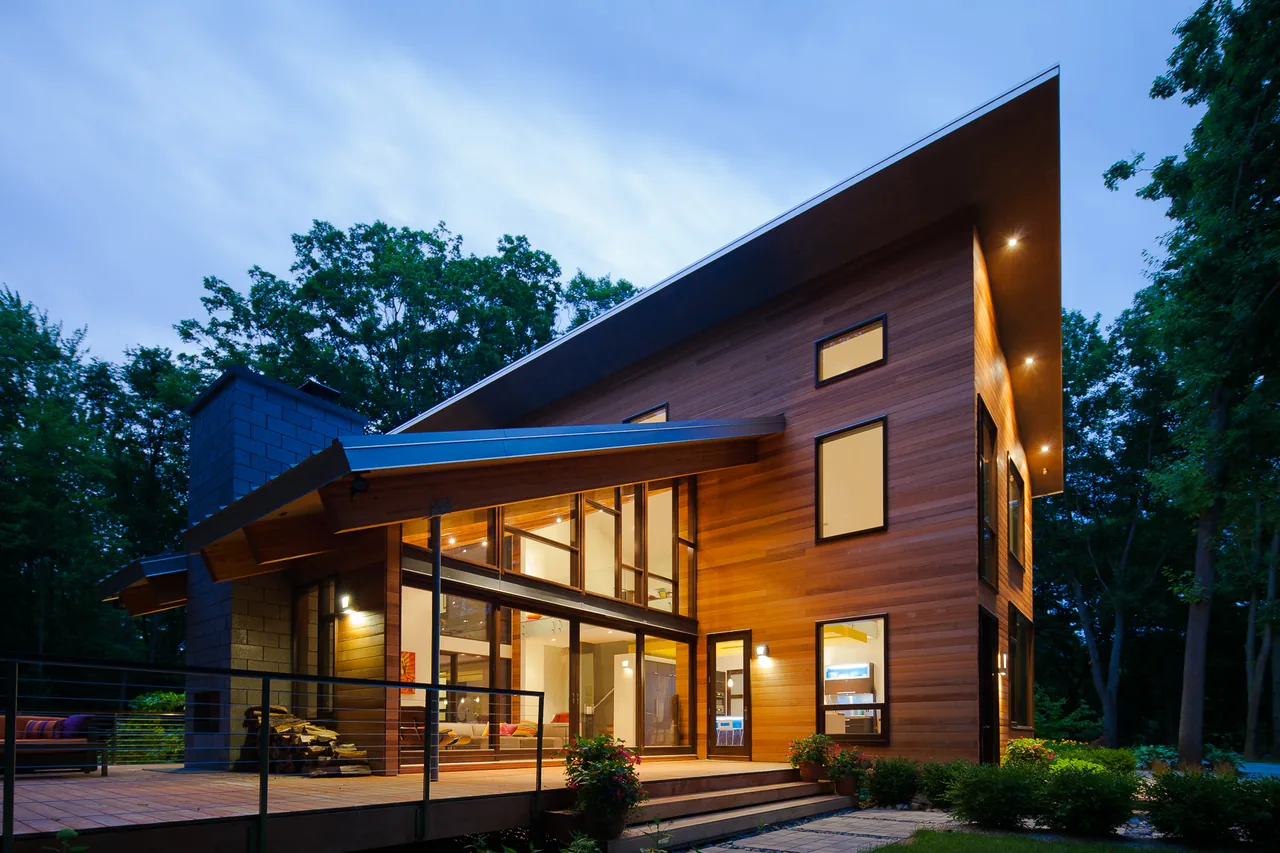 Pigeon Creek Residence features modern design with large wood siding, angled roof, and extensive glazing on its front exterior.