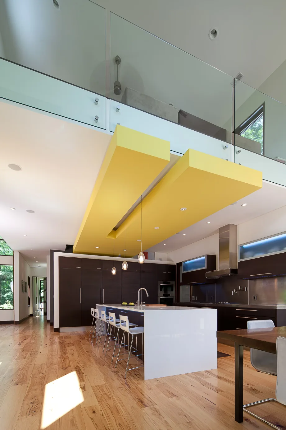 Pigeon Creek Residence kitchen with a white island, dark wood cabinetry, and a bold yellow suspended ceiling element.