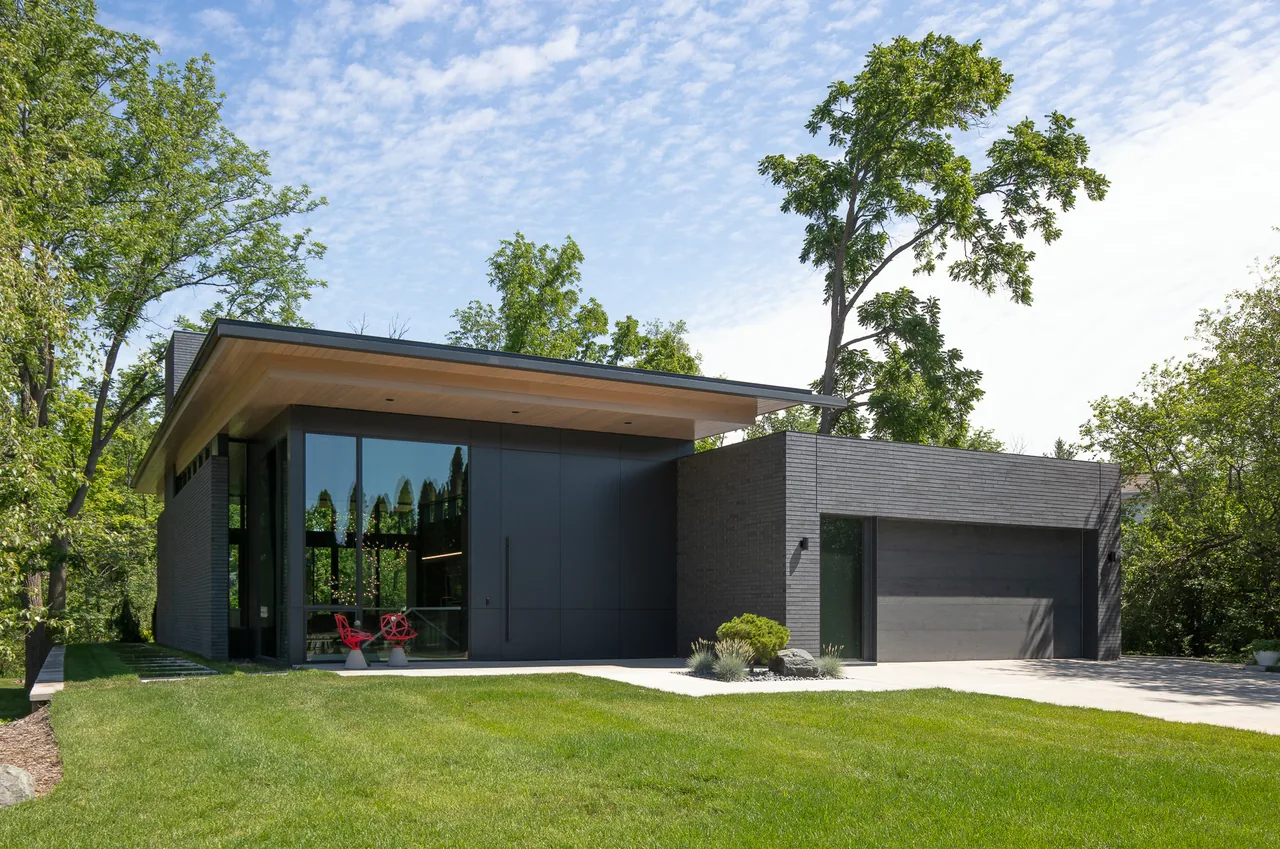 Mercer Residence by Lucid Architecture features dark brick walls, large floor-to-ceiling windows, and a flat roof design.