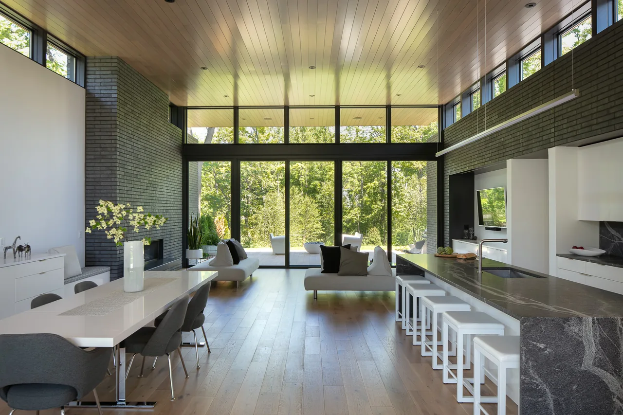 Modern Mercer Residence living area features black brick walls, wood ceiling, and expansive glass doors to the outdoors.