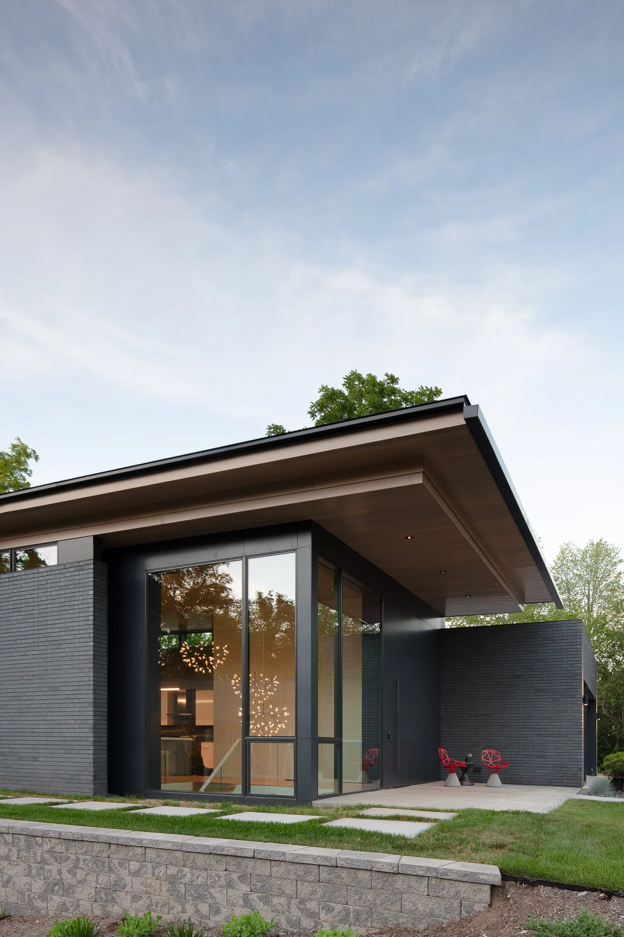 Mercer Residence features a modern exterior with black brick walls, large glazed windows, and a flat roof with wood soffits.