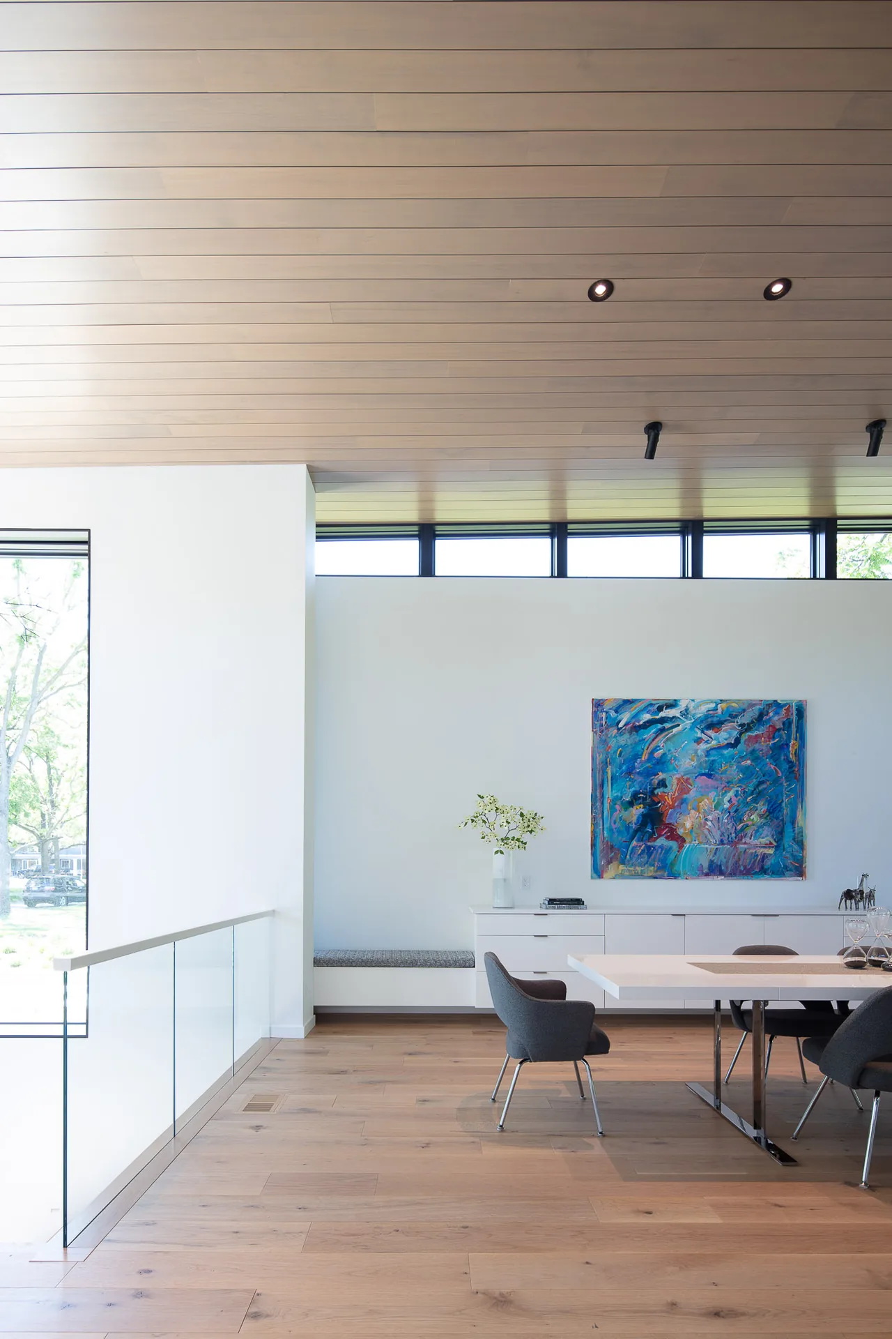Dining area of Mercer Residence with wood flooring, modern furniture, and abstract painting by Lucid Architecture.
