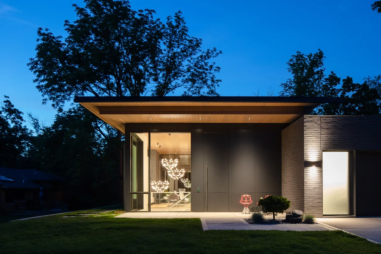 Mercer Residence features a modern exterior with flat roof and floor-to-ceiling glazing, captured at dusk showing interior lighting.