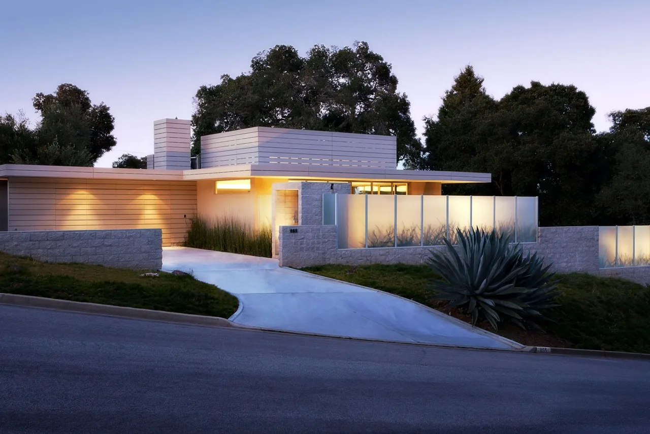 Modern Olson Residence with flat roof and illuminated exterior walls at dusk.