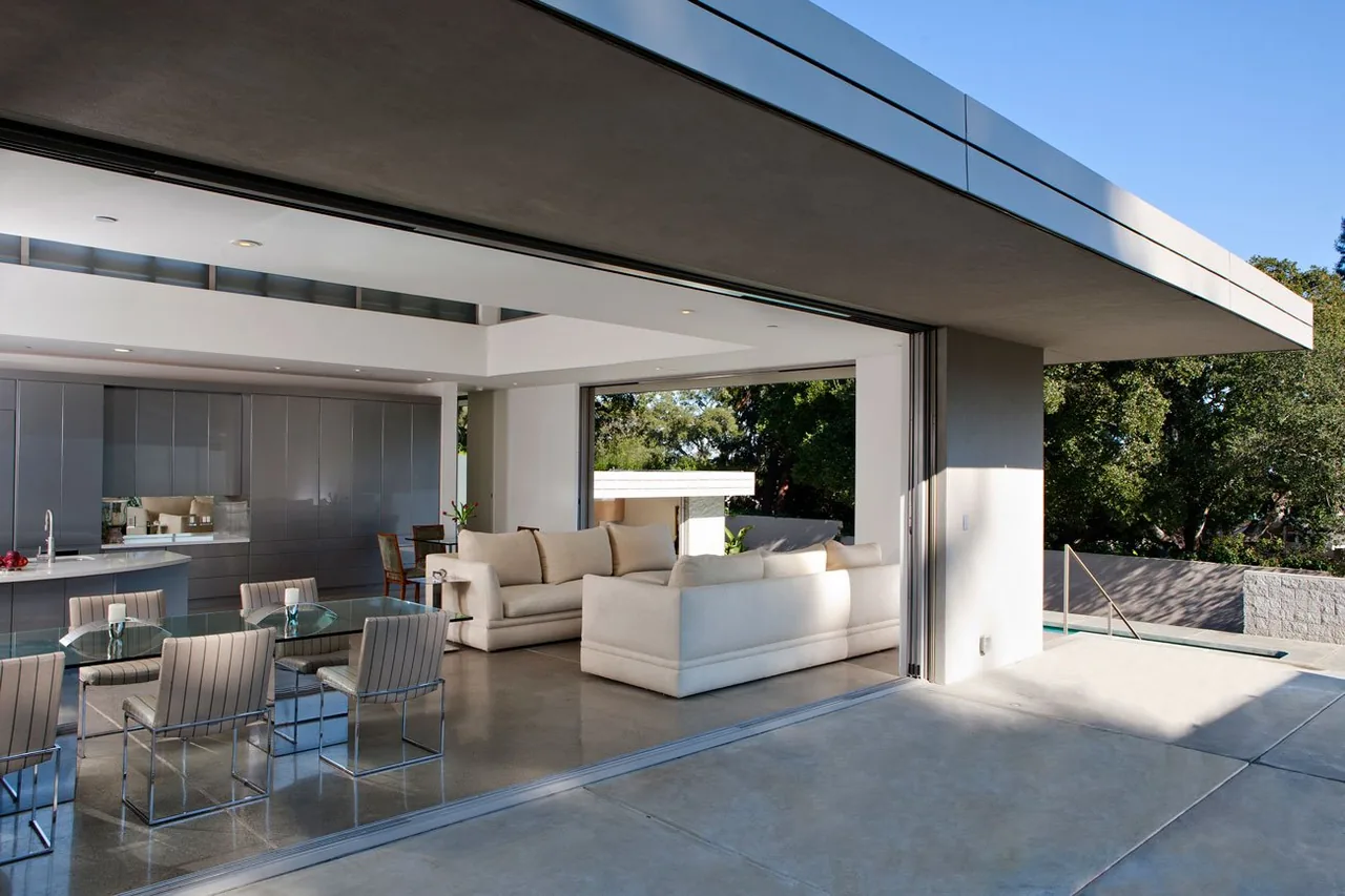 The Olson Residence features a seamless indoor-outdoor living space with concrete floors and modern furnishings.
