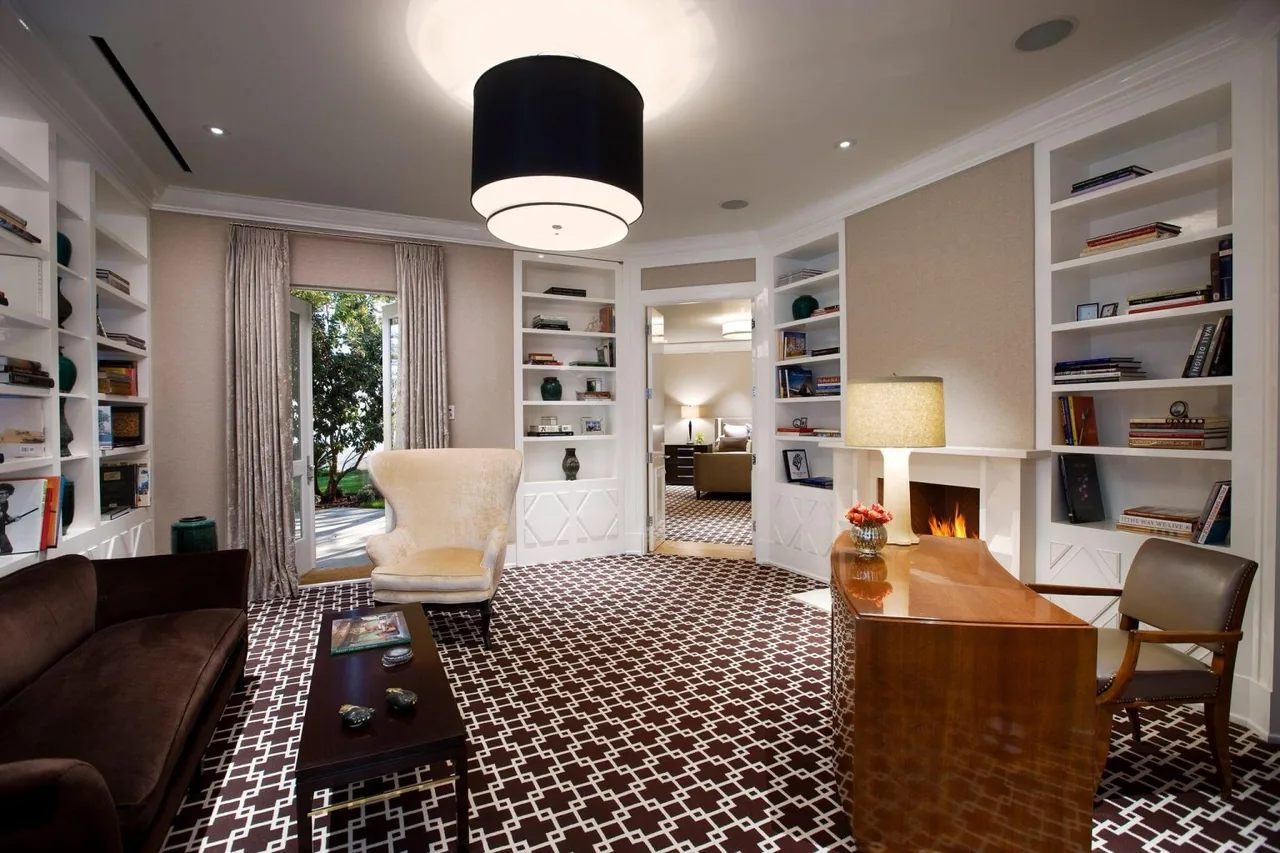Living room featuring built-in white bookshelves, patterned carpeting, and a fireplace, with access to an outdoor space.