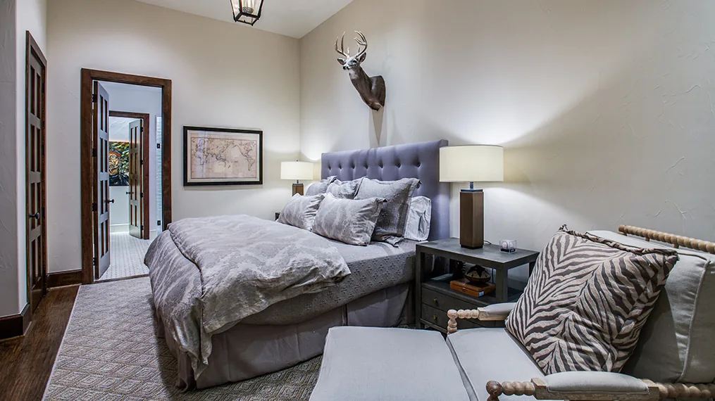 Bedroom featuring a tufted bed, mounted deer head decor, and accessory seating with a zebra print cushion.