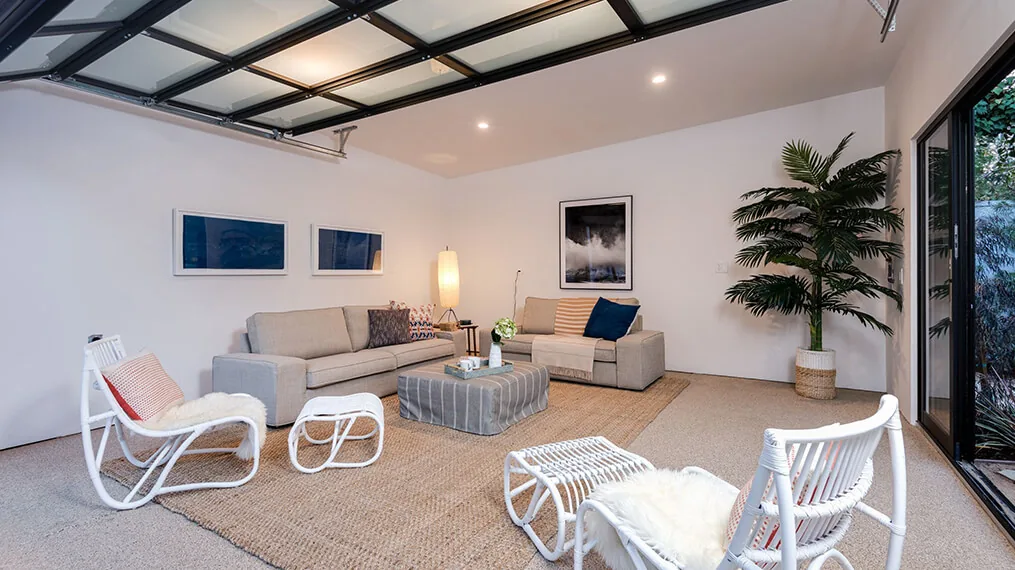 Living room featuring beige sofas, white wicker chairs, carpeted floor, and large glass sliding door to the outdoors.