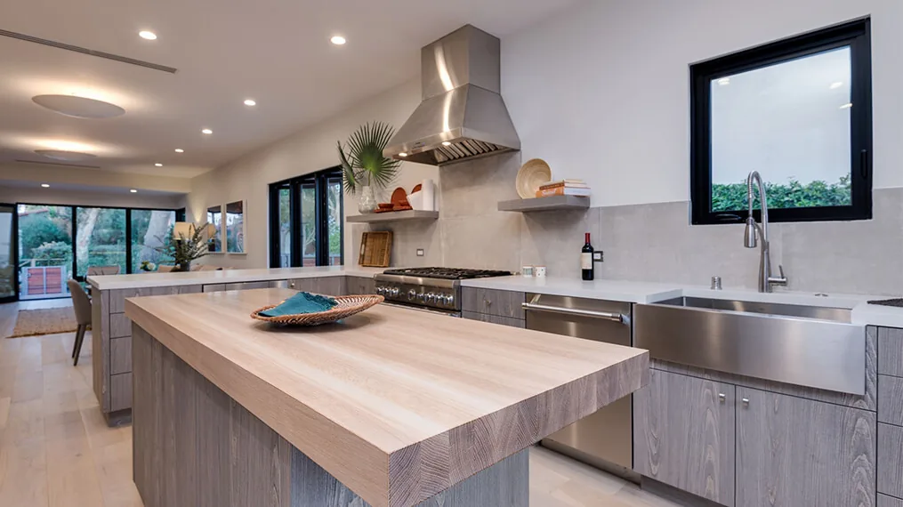 Kitchen of the Los Angeles Modern Bungalow featuring a wood island and stainless steel farmhouse sink.